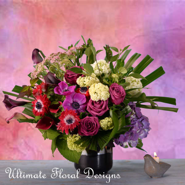 Mixed bouquet of pink, purple, and white flowers in a black vase