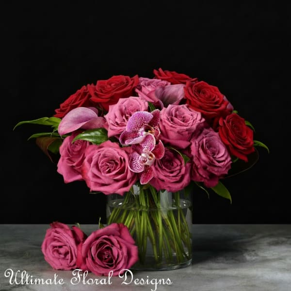 Pink and red roses with orchids in a glass vase