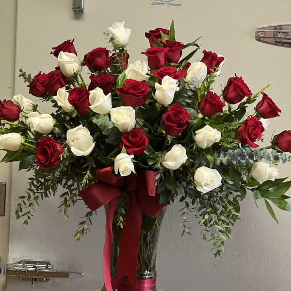 Large bouquet of red and white roses in a glass vase with a red ribbon