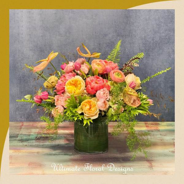 Colorful bouquet of pink, peach, and yellow flowers in a green glass vase