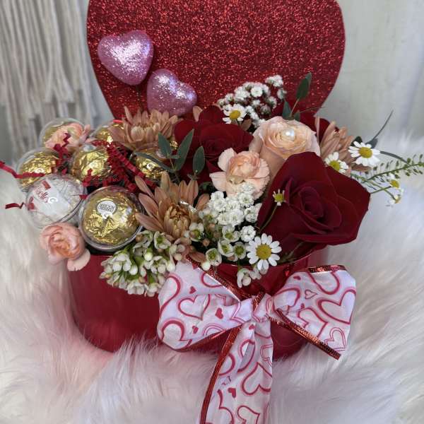 Heart-shaped gift arrangement with roses, daisies, and chocolates