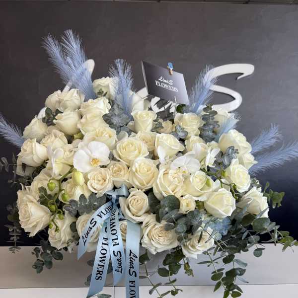 Bouquet of white roses with blue feathers and eucalyptus