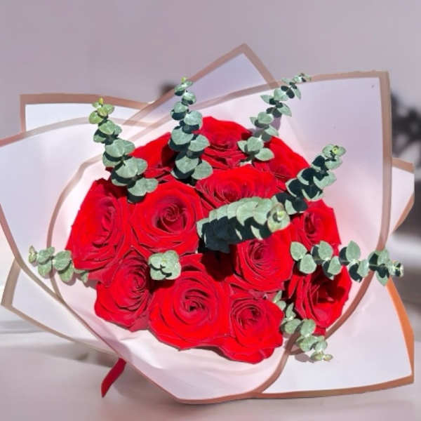 Bouquet of red roses with eucalyptus in white wrapping