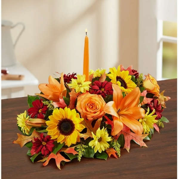 Autumn floral centerpiece with orange lilies, sunflowers, and a candle