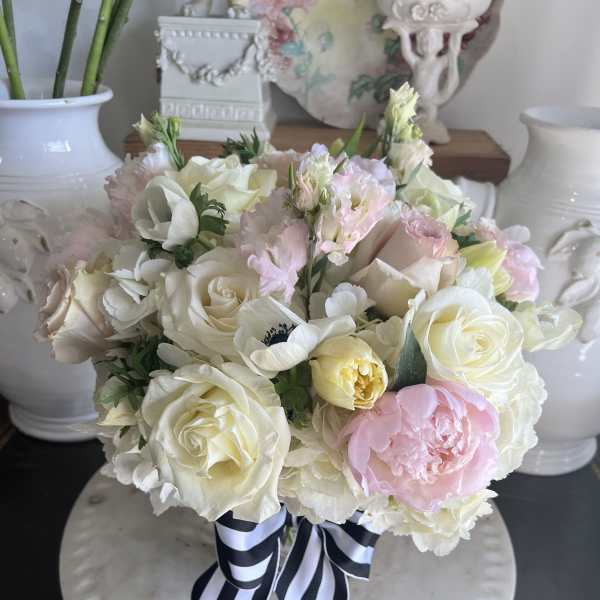 Pastel bouquet of roses, peonies, and white blooms tied with a striped ribbon