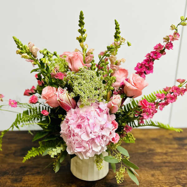 Pink floral arrangement in a white vase with tall spiky blooms