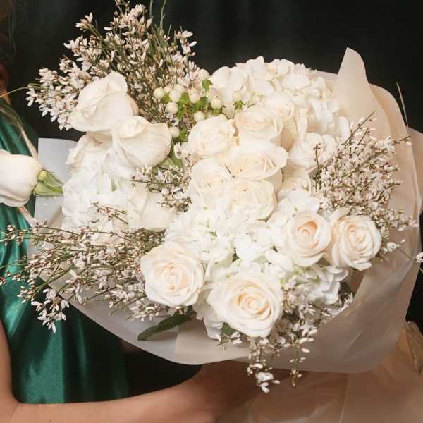 Bouquet of white roses and hydrangeas wrapped in pale paper