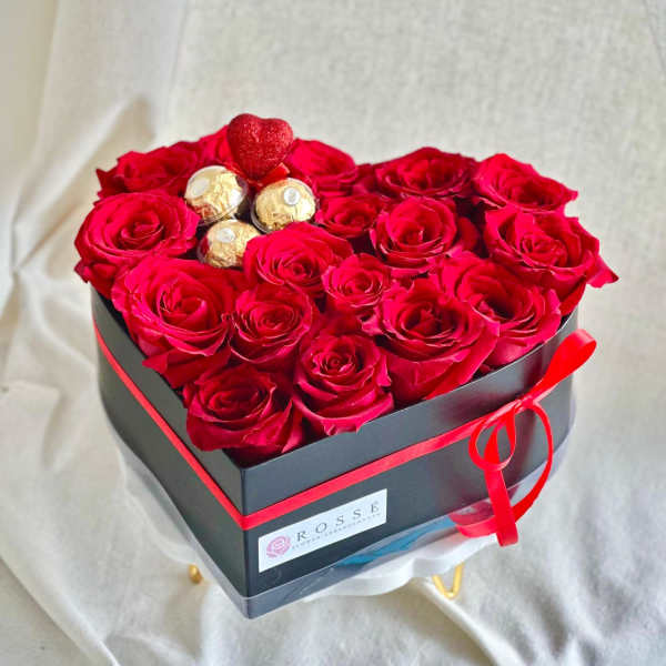 Heart-shaped box of red roses with chocolates and a small heart topper