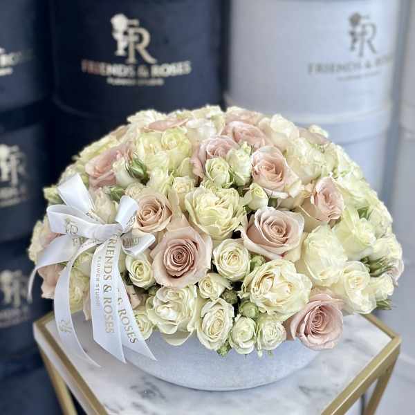 Round bouquet of pale pink and ivory roses in a white box with a ribbon.