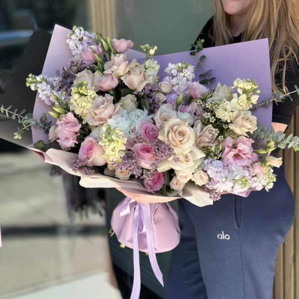 Large pastel bouquet of roses, lisianthus, and stock wrapped in lavender paper