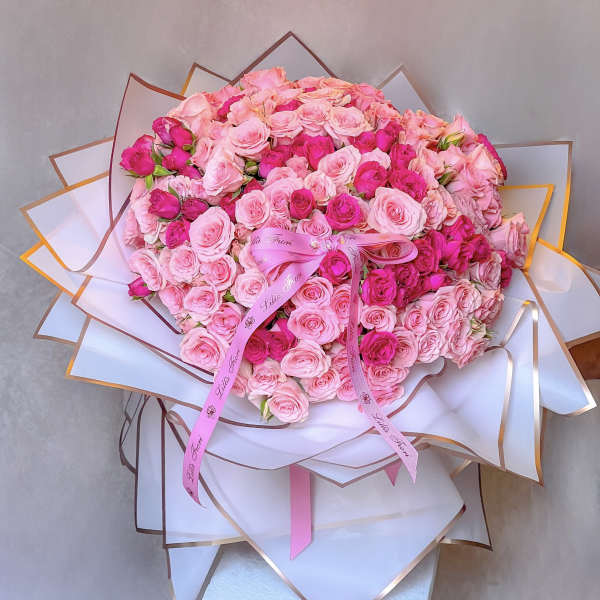 Large bouquet of pink roses wrapped in white paper with a pink ribbon
