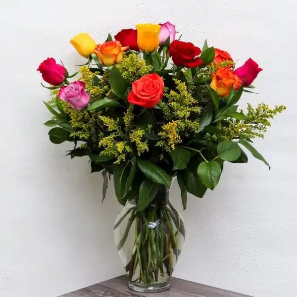 Mixed roses in a clear glass vase with greenery