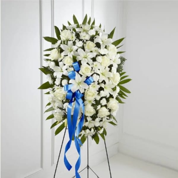White funeral spray on a stand with a blue ribbon
