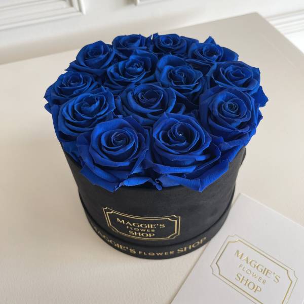 Blue roses arranged in a black round box