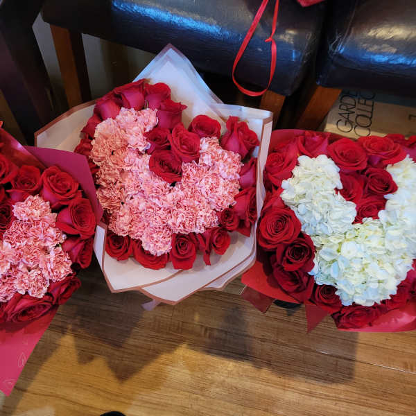 Three bouquets of red roses and pink carnations, one with white hydrangeas
