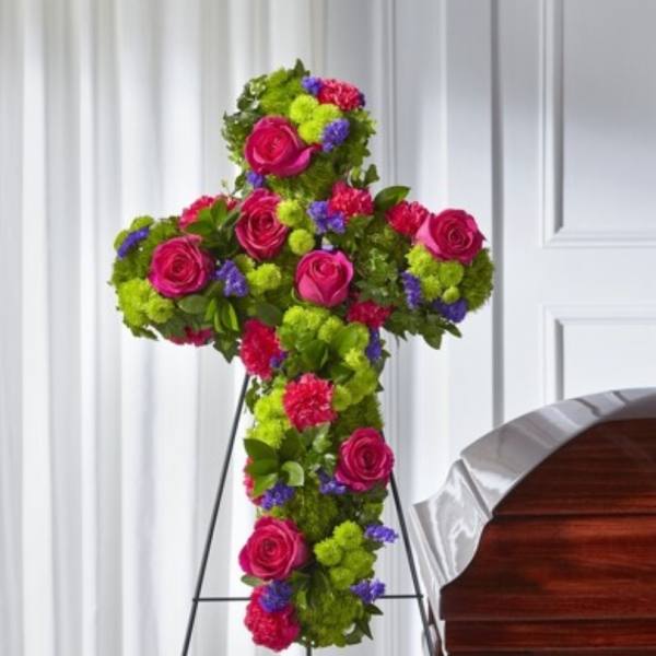 Cross-shaped floral tribute with pink roses and bright mixed blooms