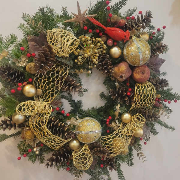 Christmas wreath with pinecones, gold ornaments, and a red cardinal