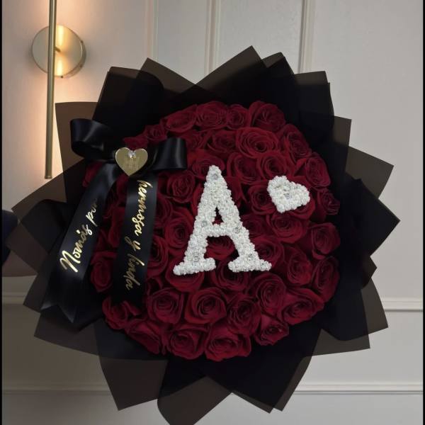 Round bouquet of deep red roses with black wrapping and a white letter A