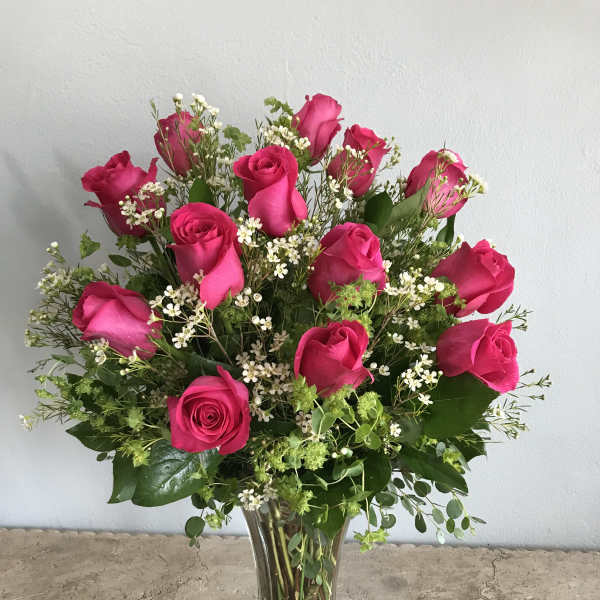 Pink roses arranged in a clear glass vase with small white filler flowers
