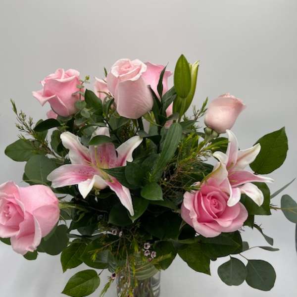 Pink roses and pink lilies arranged in a clear glass vase