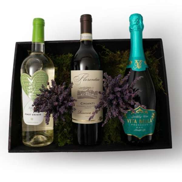 Gift box with three assorted wine bottles nestled in moss with purple dried sprigs
