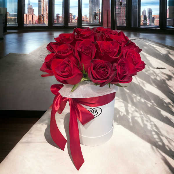 Red roses arranged in a white hatbox with a red ribbon