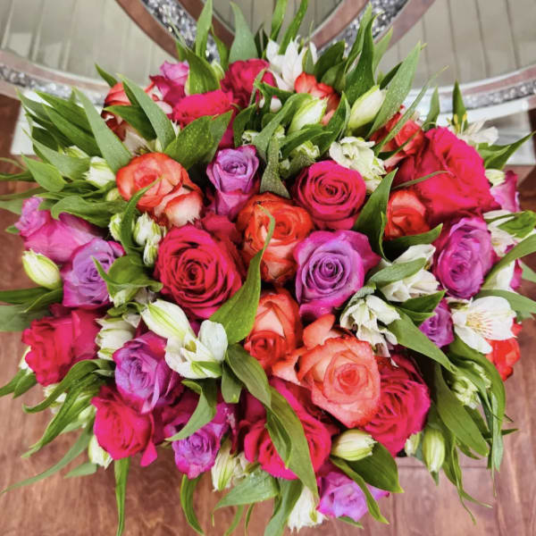 Bouquet of pink, purple, and coral roses with white accent flowers