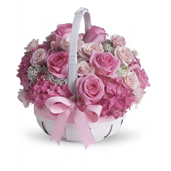 Pink roses and hydrangeas arranged in a white basket with a ribbon handle