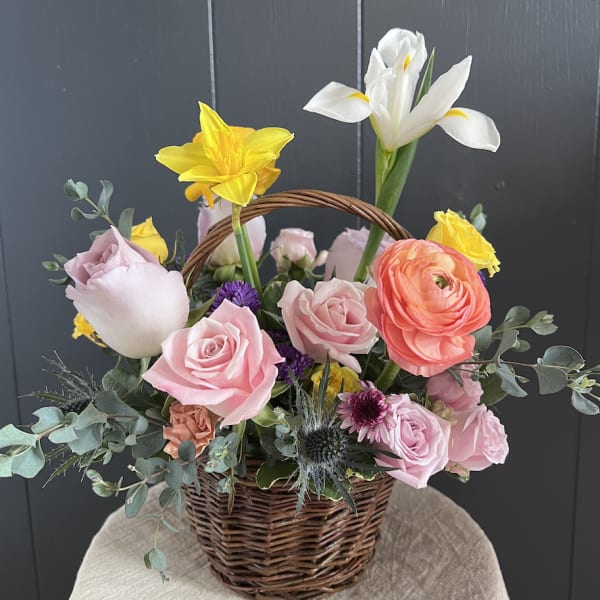 Basket arrangement with pink roses, yellow daffodils, and white iris