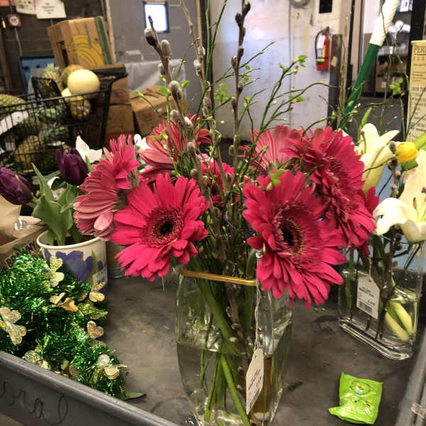 Pink gerbera daisies in a glass vase with tulips and pussy willow branches