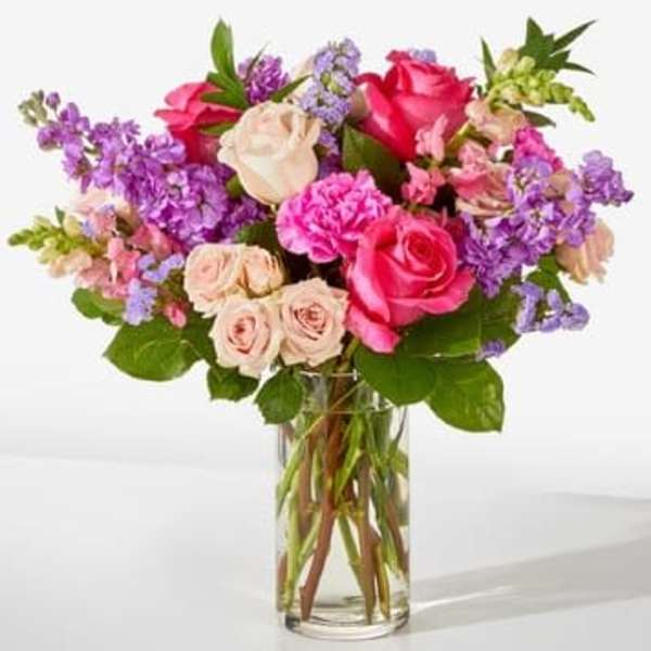 Bouquet of pink and purple flowers in a clear glass vase