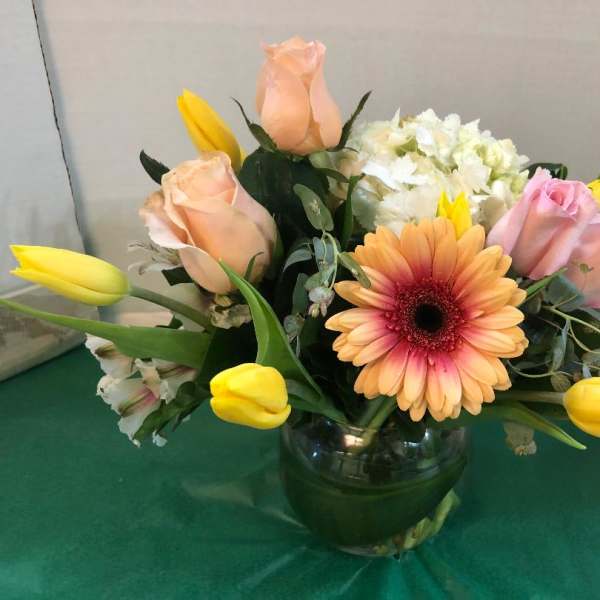 Mixed bouquet with roses, tulips, and a gerbera daisy in a glass vase