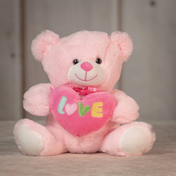 Pink teddy bear holding a heart with the word LOVE