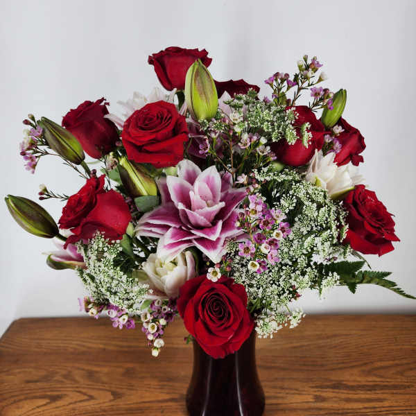 Bouquet of red roses and pink lilies in a dark vase