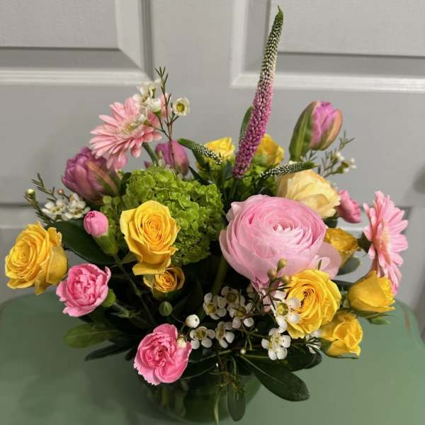 Mixed bouquet of pink and yellow flowers in a glass vase