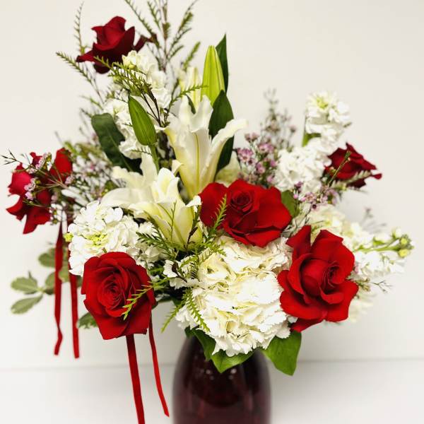 Red roses and white lilies arranged in a dark vase