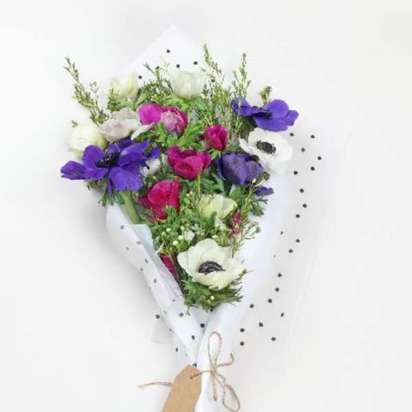 Bouquet of purple, pink, and white flowers wrapped in white paper