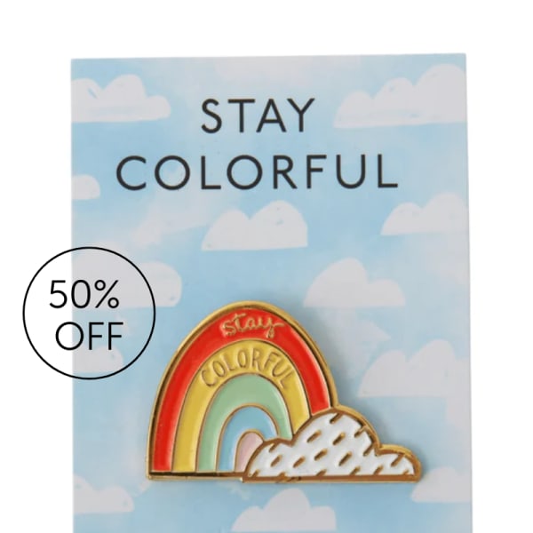 Enamel pin on a cloud-patterned card with a rainbow design