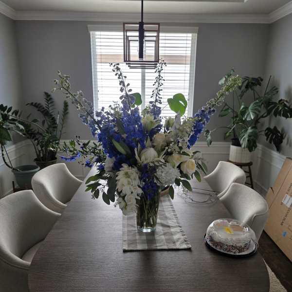 Blue and white floral arrangement in a clear glass vase on a dining table