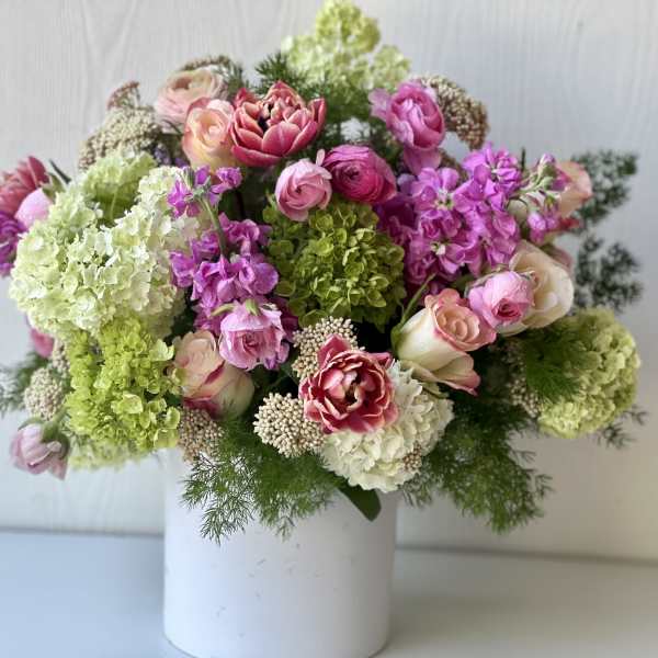 Mixed pink and green floral arrangement in a white vase