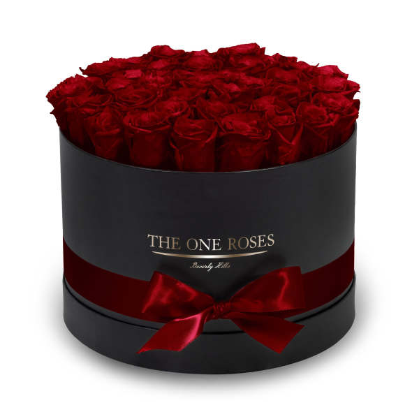 Round box filled with red roses and tied with a red ribbon