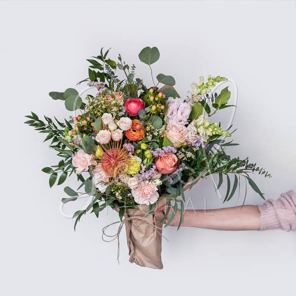 Handheld bouquet of mixed pink and peach flowers with greenery