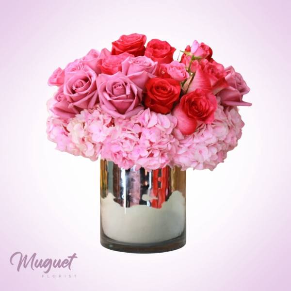 Pink and red roses arranged in a mirrored vase