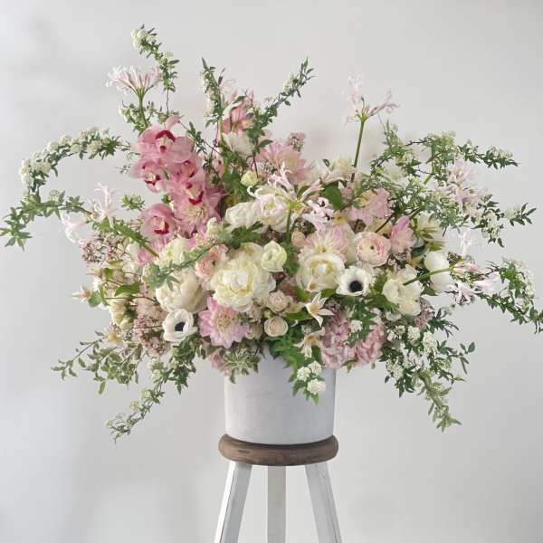 Large pink and white floral arrangement in a white vase