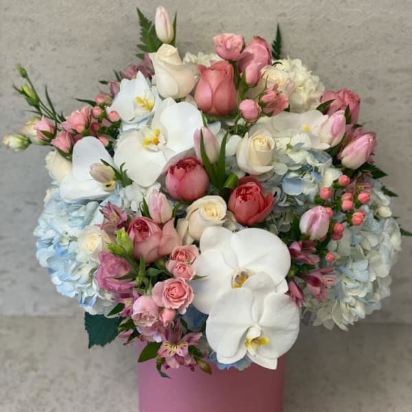 Pink and white bouquet with orchids, roses, and hydrangeas in a pink box