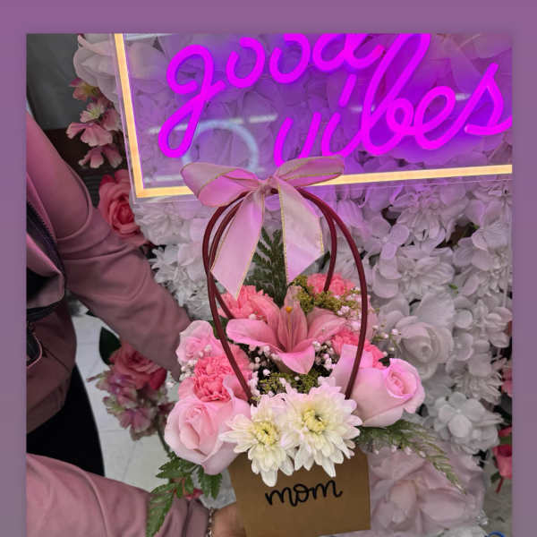 Pink flower basket with roses and daisies, topped with a ribbon bow