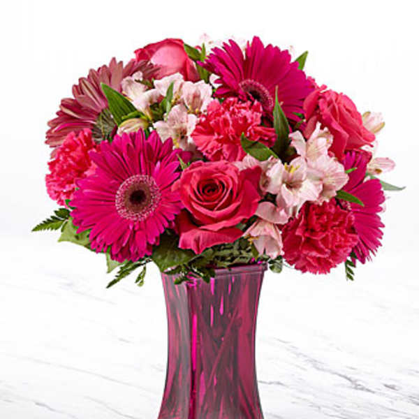 Pink mixed flower bouquet in a tall magenta vase
