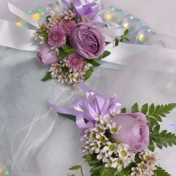 Two lavender floral corsages with ribbon bows and tulle