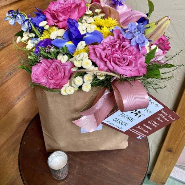 Mixed bouquet in a kraft paper bag with pink ribbon