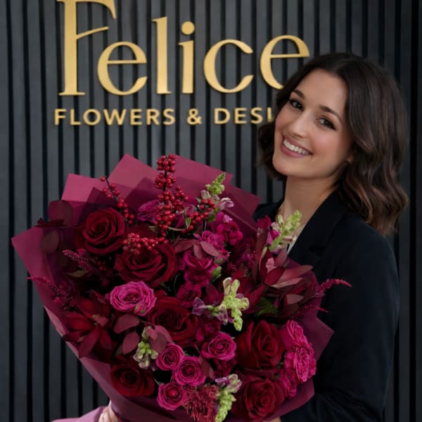 Woman holding a large bouquet of deep pink and red roses